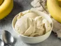 Delicioso helado de plátano cremoso en un tazón blanco, con plátanos amarillos frescos al lado.
