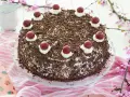 Deliciosa tarta Selva Negra, cubierta de virutas de chocolate y coronada con cerezas y nata.