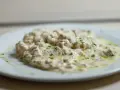 Deliciosa brandada de bacalao cremosa, con trozos de pescado blanco y perejil picado, servida en un plato blanco.