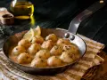 Albondigas de pollo caseras en salsa cremosa, servidas en sartén con limón y hierbas.