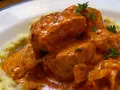 Sabroso pavo en salsa cremosa, con trozos de carne tierna y un toque de hierbas frescas, servido sobre puré de patatas.