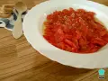 Asadillo manchego, pimientos asados con ajo y aceite, listos para disfrutar con tostadas y una cuchara de madera.