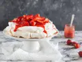 Deliciosa tarta pavlova con fresas frescas y salsa de fresa, lista para ser disfrutada.