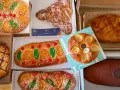 Variedad de cocas de Sant Joan, algunas decoradas con fruta confitada, piñones y almendras. ¡Una delicia para celebrar!