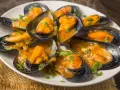 Mejillones en salsa, humeantes y listos para disfrutar. Un plato delicioso con un toque de perejil fresco.