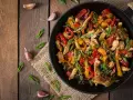 Sabroso wok de pollo con pimientos de colores y judías verdes, espolvoreado con semillas de sésamo y cebolleta.
