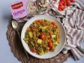 Un plato de quinoa con verduras, incluyendo tomates cherry, calabacín y zanahoria, listo para disfrutar.