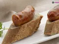 Chorizo a la sidra jugoso sobre pan rústico, decorado con perejil fresco. Un bocado delicioso.