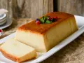 Un delicioso pudin de pan, con una capa dorada y decorado con frutos rojos y menta.