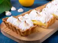 Tarta de limón con merengue suizo tostado, decorada con picos dorados.