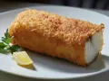 Un trozo de bacalao rebozado y dorado, servido con perejil y limón. Perfecto para tus recetas de bacalao.