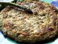 Tortilla de esparragos dorada y esponjosa, con espárragos frescos encima, servida en un plato azul.