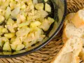 Zarangollo murciano, un revuelto de calabacín y cebolla, servido en sartén con pan rústico.