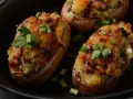 Deliciosas patatas rellenas, doradas y gratinadas, adornadas con cebolleta y perejil fresco.