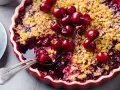 Delicioso postre con cerezas, cubierto de crumble dorado y adornado con cerezas frescas.