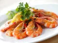 Plato de gambas al ajillo, jugosas y doradas, adornadas con perejil fresco y rodajas de limón.