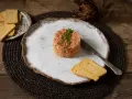 Delicioso tartar de tomate, servido con tostas crujientes y un cuchillo de plata. Un plato fresco y vibrante.