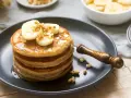 Pila de tortitas americanas con plátano, nueces y sirope. Un desayuno delicioso y nutritivo.