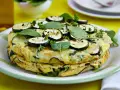 Deliciosa tortilla de calabacín y espinacas, coronada con rodajas de calabacín y hierbas frescas.