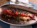 Un langostino rojo a la parrilla, servido sobre cebolla caramelizada y adornado con cebollino. Un plato que evoca la pregunta: ¿qué son los carabineros?