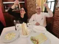 Pareja sonriente celebra con espárragos blancos en un restaurante. Platos de espárragos blancos y ensalada adornan la mesa.