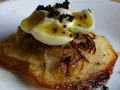 Delicioso aperitivo con patatas crujientes, cebolla frita, huevos de codorniz cocidos y caviar negro.
