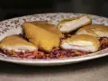 Pechuga villaroy dorada y crujiente, rellena de queso fundido, servida sobre una ensalada de col morada y zanahoria.
