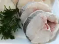 Rodajas de merluza de pincho, frescas y listas para cocinar, acompañadas de perejil.