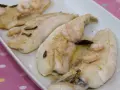 Filetes de gallo a la plancha con gambas y ajo laminado, servidos en una bandeja blanca.