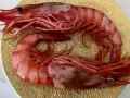 Dos gambas rojas, de distintos tipos, descansan sobre un plato dorado.