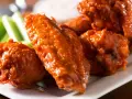Alitas de pollo en freidora de aire, cubiertas de salsa picante, servidas con bastones de apio crujientes.