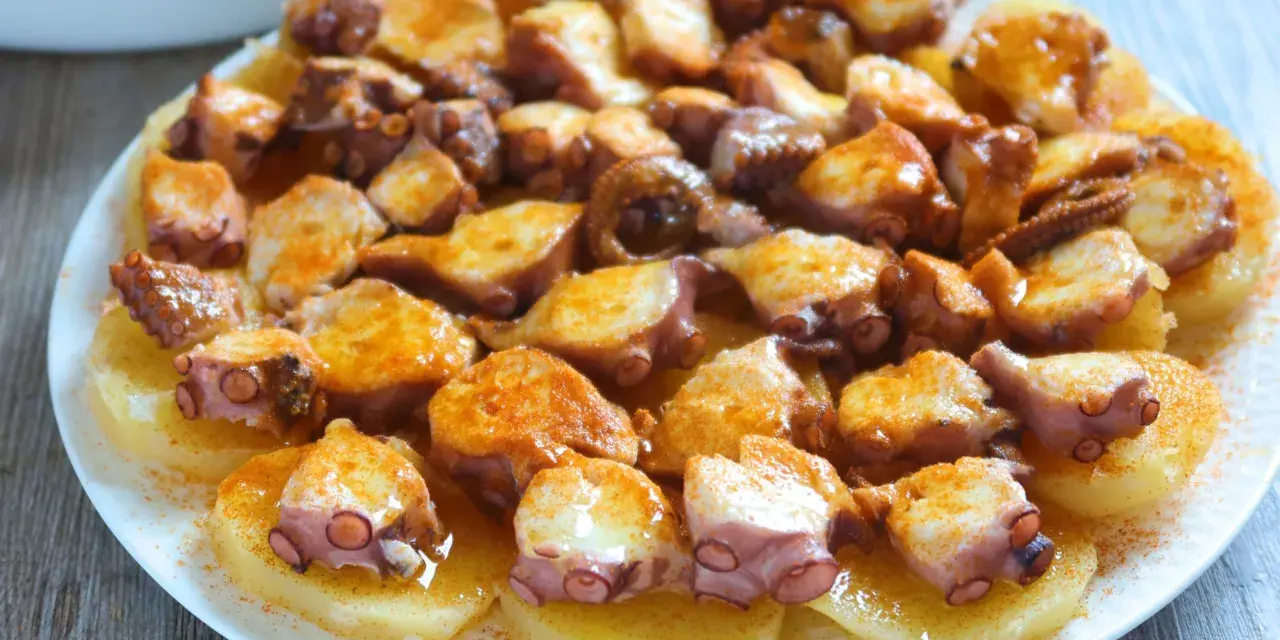 Pulpo a la gallega servido sobre patatas cocidas, con pimentón espolvoreado. ¡Un plato delicioso!