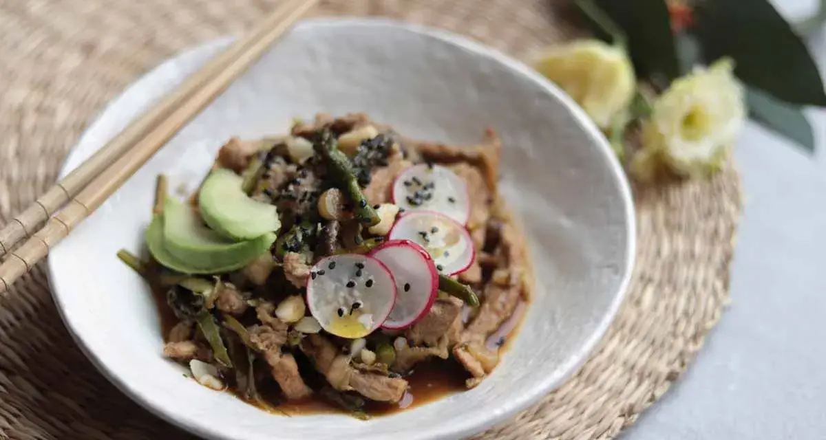 Delicioso wok de verduras con tiras de carne, aguacate, rábano y semillas de sésamo.