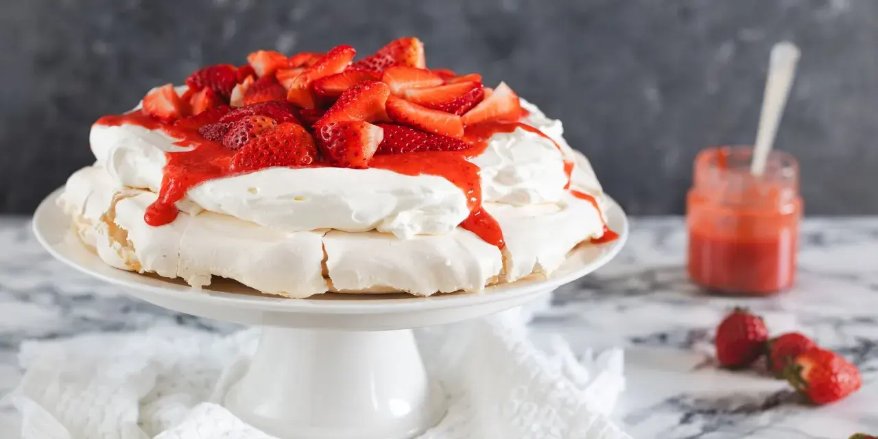 Deliciosa tarta pavlova con fresas frescas y salsa de fresa, lista para ser disfrutada.