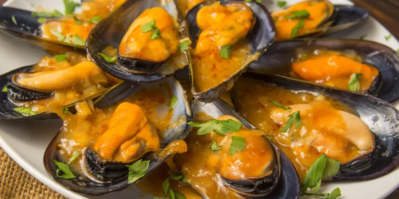 Mejillones en salsa, humeantes y listos para disfrutar. Un plato delicioso con un toque de perejil fresco.