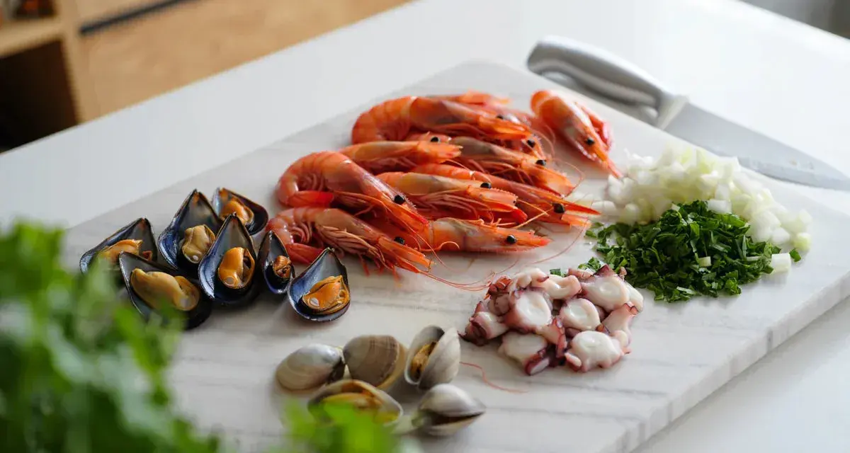 Ingredientes listos para un delicioso salpicón de marisco: gambas, mejillones, pulpo, almejas, cebolla y perejil picados.