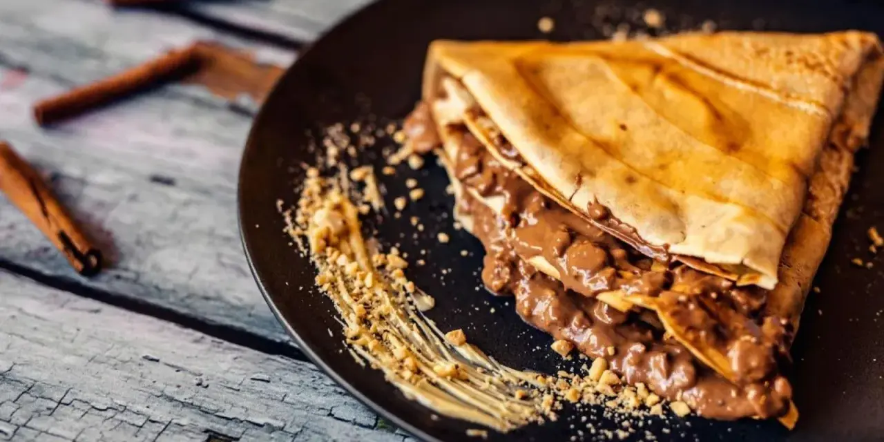 Crepe doblada con relleno cremoso de chocolate y trocitos de frutos secos. Ideal para aprender como hacer crepes deliciosos.