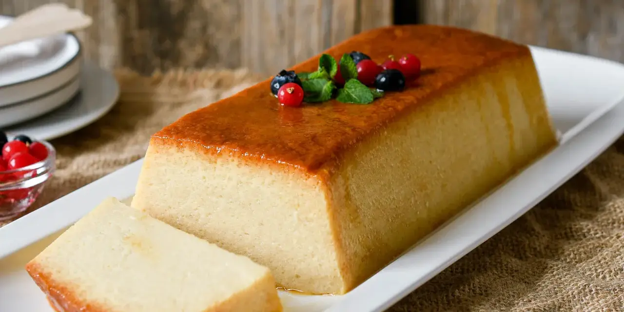 Un delicioso pudin de pan, con una capa dorada y decorado con frutos rojos y menta.