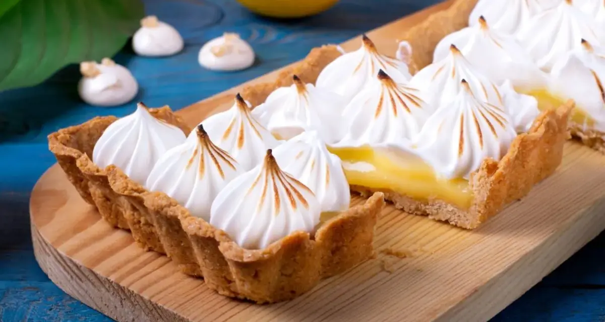Tarta de limón con merengue suizo tostado, decorada con picos dorados.