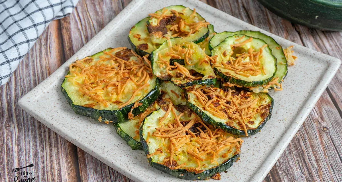 Rodajas de calabacín en freidora de aire, doradas y crujientes, con un toque de queso rallado. ¡Una delicia saludable!