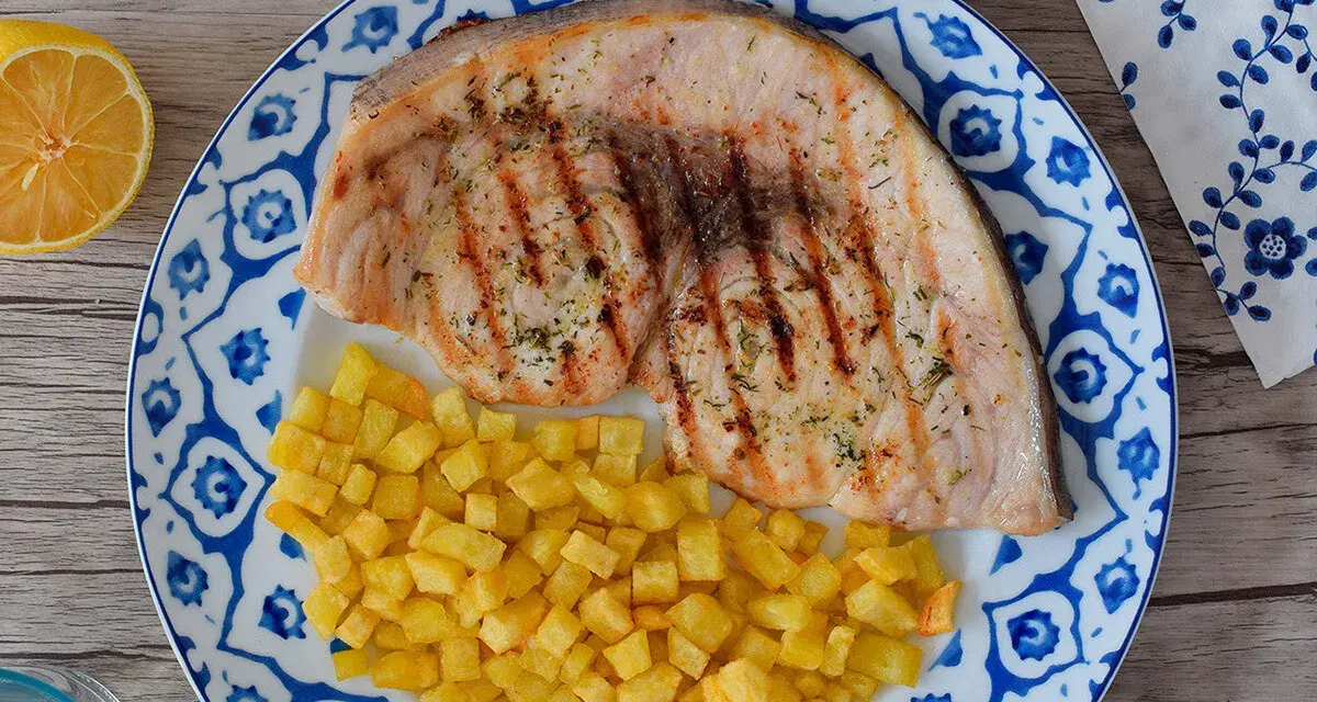 Pez espada filete a la parrilla con patatas fritas crujientes y limón. Un plato delicioso y saludable.
