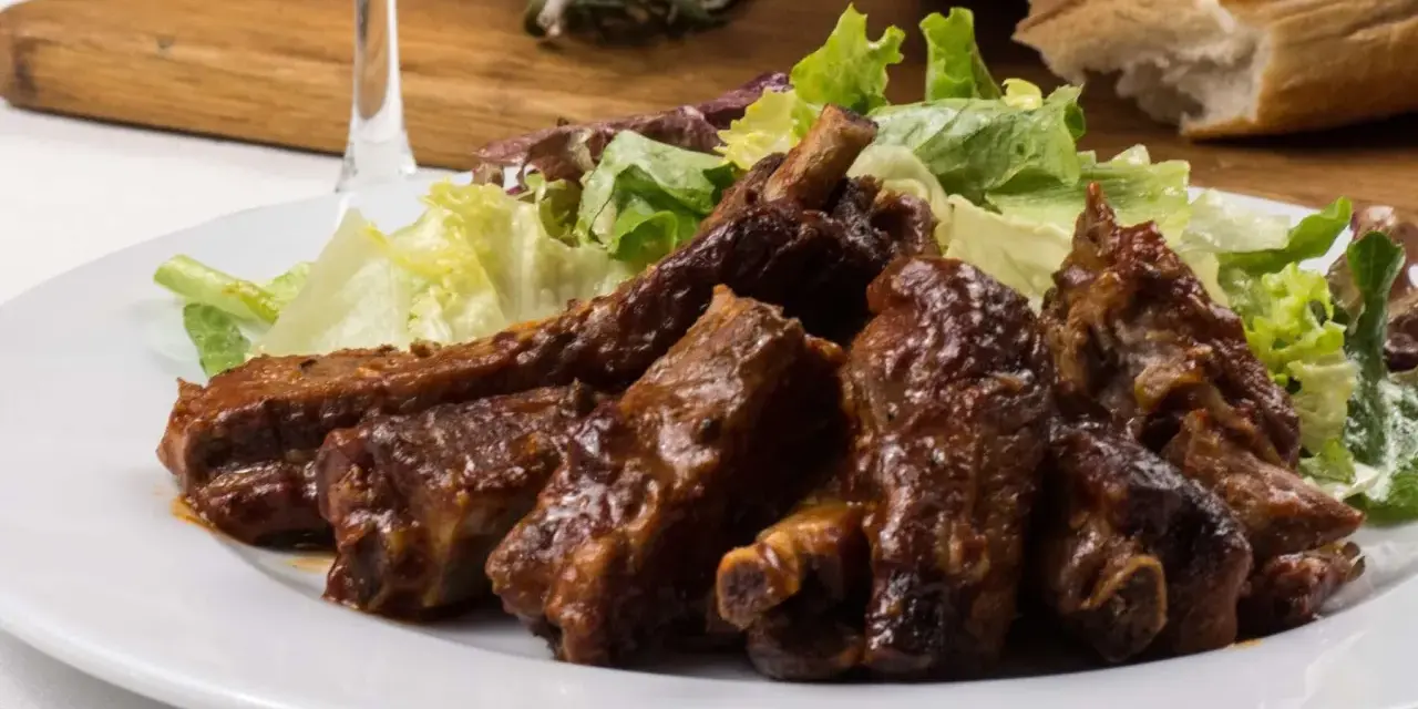 Costillas jugosas en freidora de aire, bañadas en salsa barbacoa y acompañadas de ensalada fresca. ¡Un manjar!