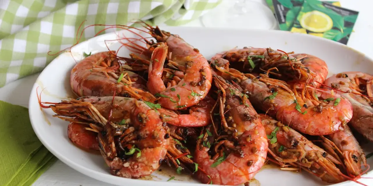 Plato de gambones al ajillo, jugosos y con perejil picado, listos para disfrutar.