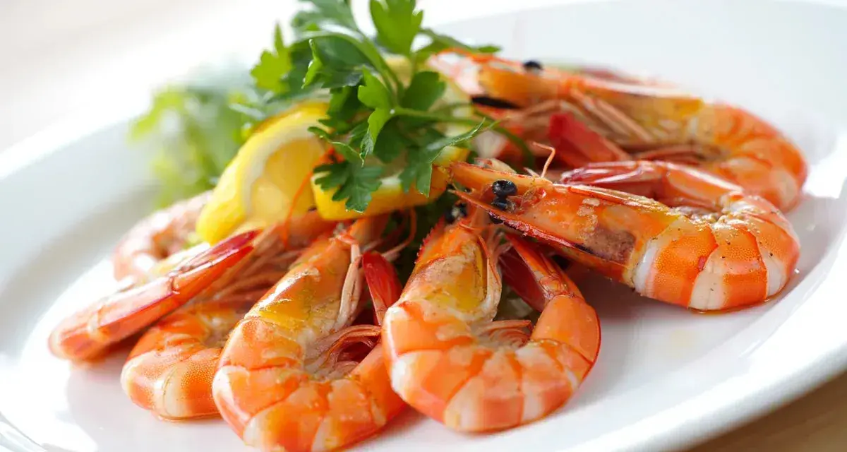 Plato de gambas al ajillo, jugosas y doradas, adornadas con perejil fresco y rodajas de limón.