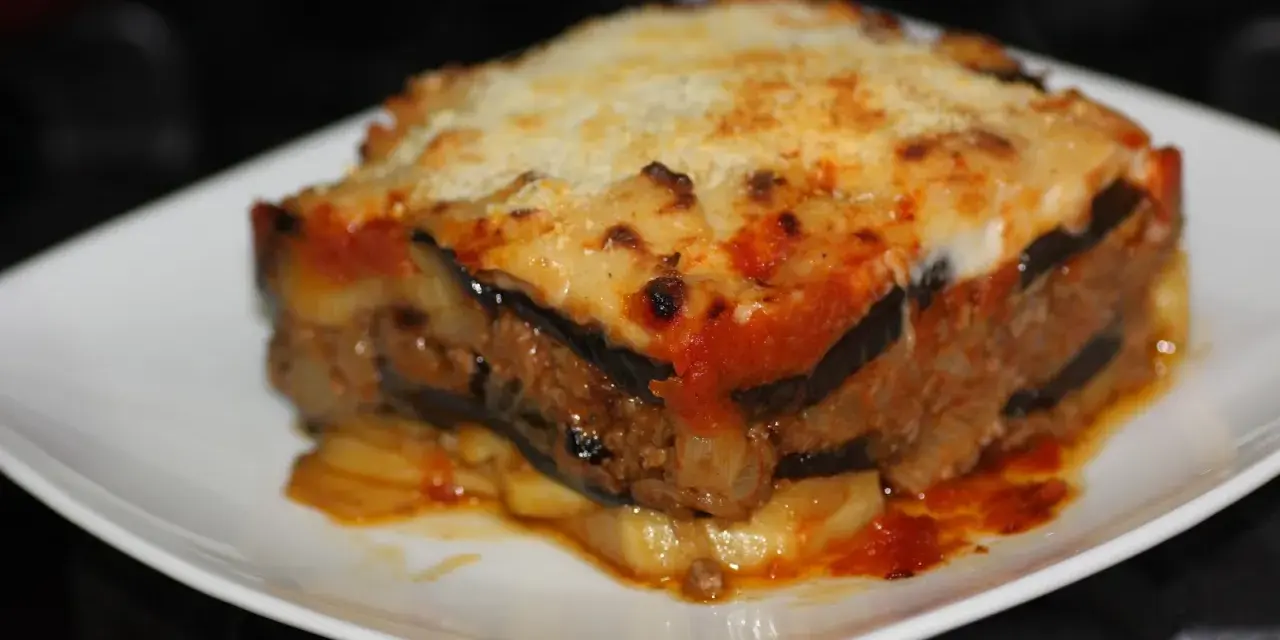 Porción de musaka casera con capas de berenjena, carne picada y salsa de tomate, gratinada con queso. ¡Una delicia de la musaka receta!