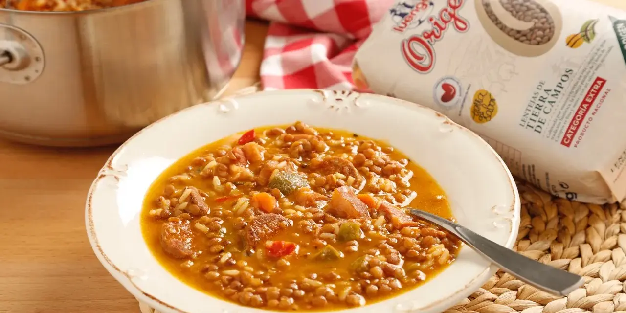 Plato de lentejas con arroz, chorizo y verduras. Una bolsa de lentejas "Origen" a un lado.