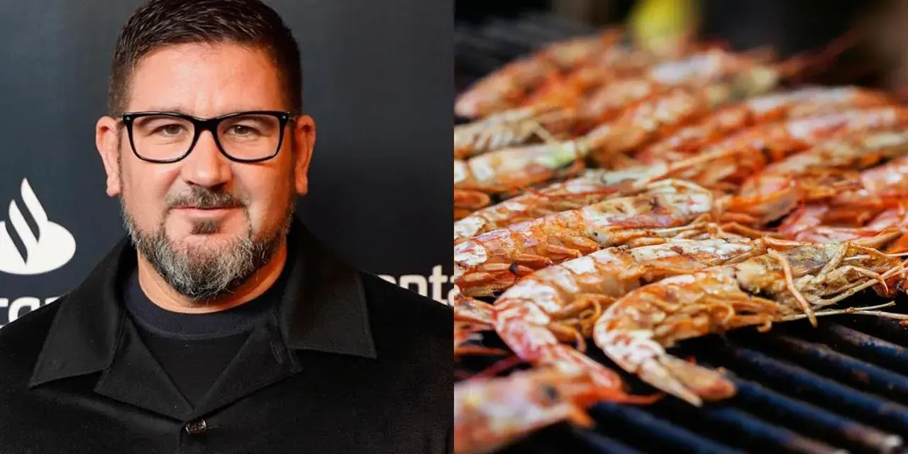 Hombre con gafas y barba junto a una parrilla llena de cigalas a la plancha, listas para ser degustadas.