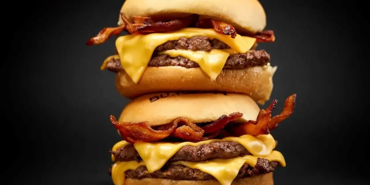 Dos hamburguesas caseras apiladas, con doble carne, queso fundido y crujiente tocino.