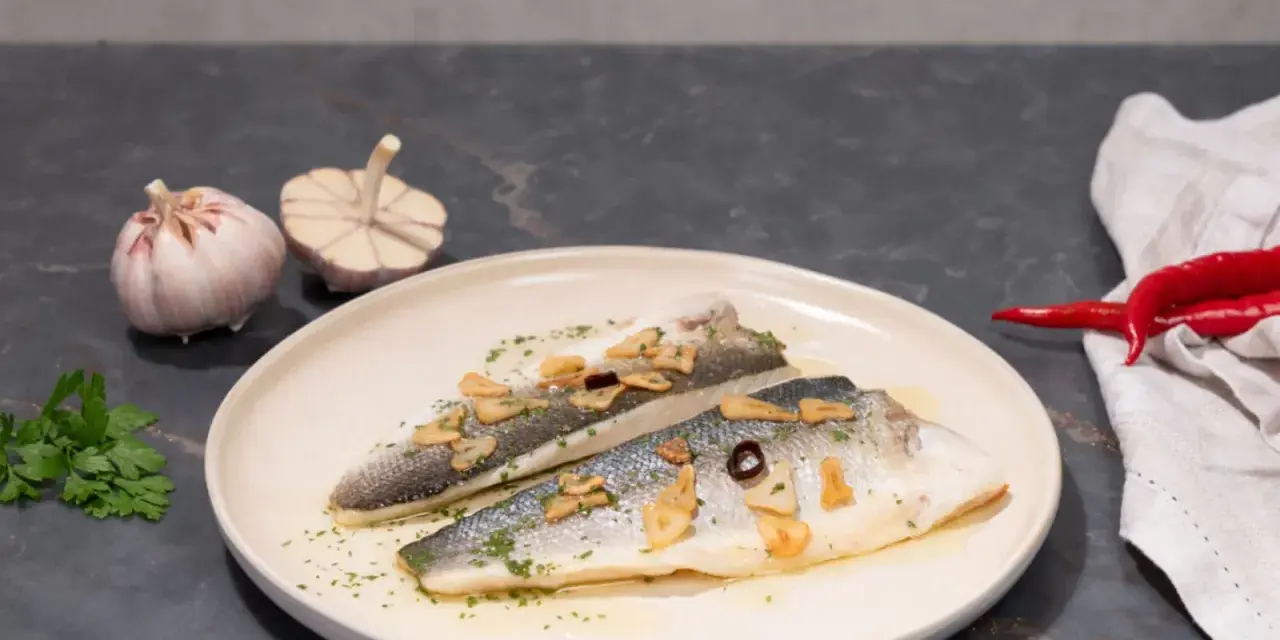 Dos filetes de lubina a la donostiarra, con láminas de ajo dorado, perejil picado y un toque de guindilla.