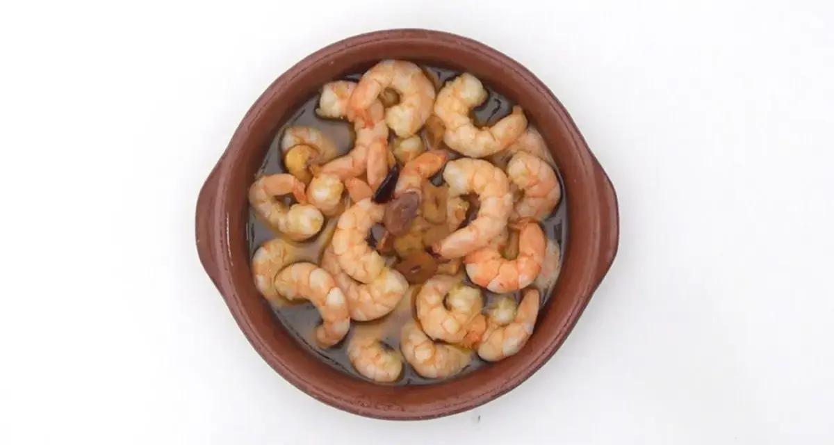 Gambas al pil pil burbujeantes en cazuela de barro, con ajo y aceite de oliva.